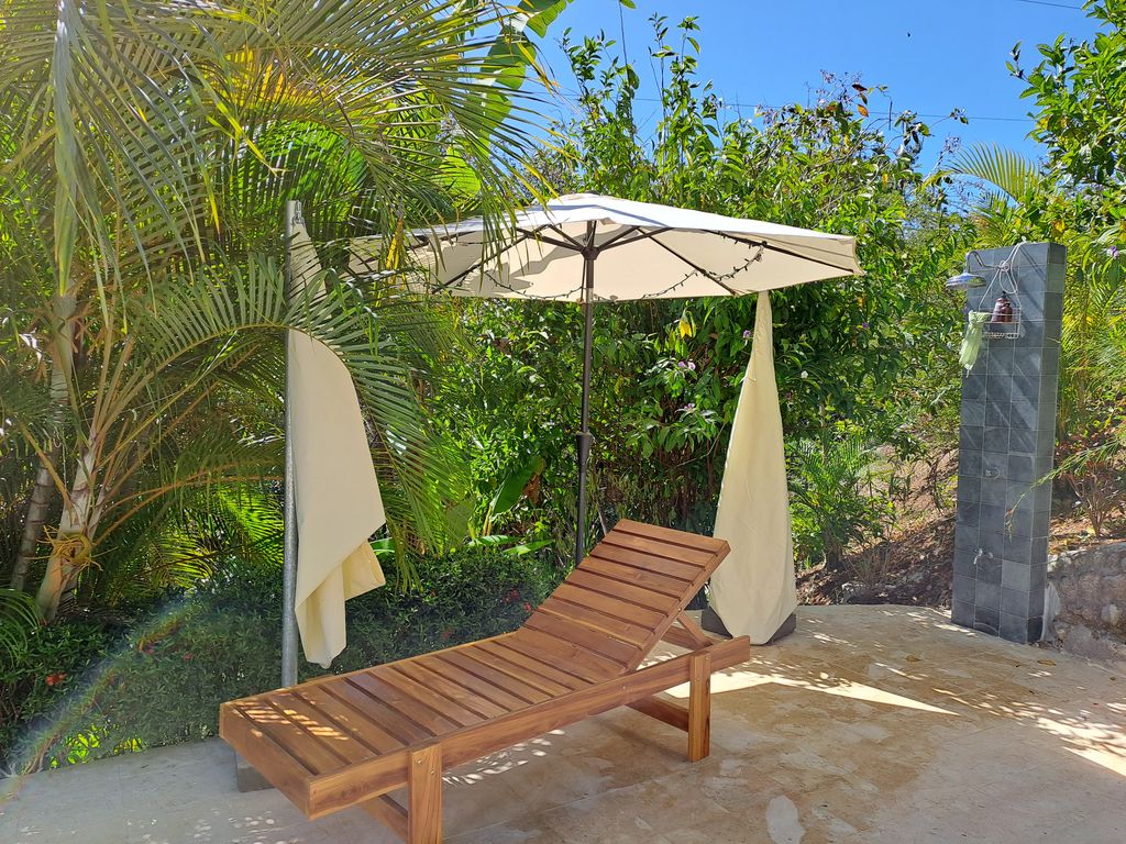 Pool chair on terrace with beach umbrella at Casa Bella Montaña, home for sale at Samara Beach, Guanacaste, Costa Rica