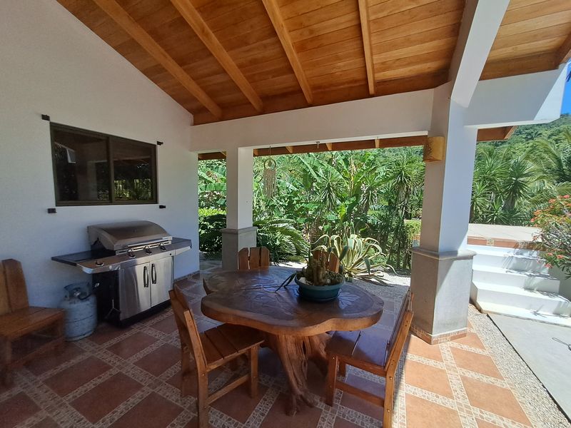Wooden table with chairs and barbecue at Casa Vista Las Palmas home for sale samara guanacaste costa rica