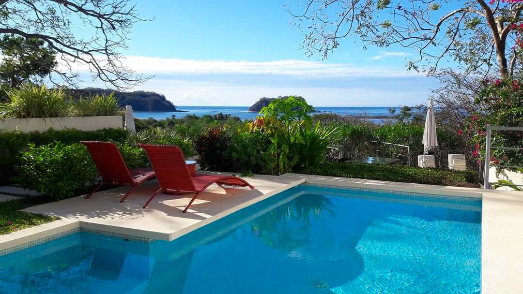 Red long chairs and pool Samara Reef Condos luxury real estate for sale samara Guanacaste Costa Rica