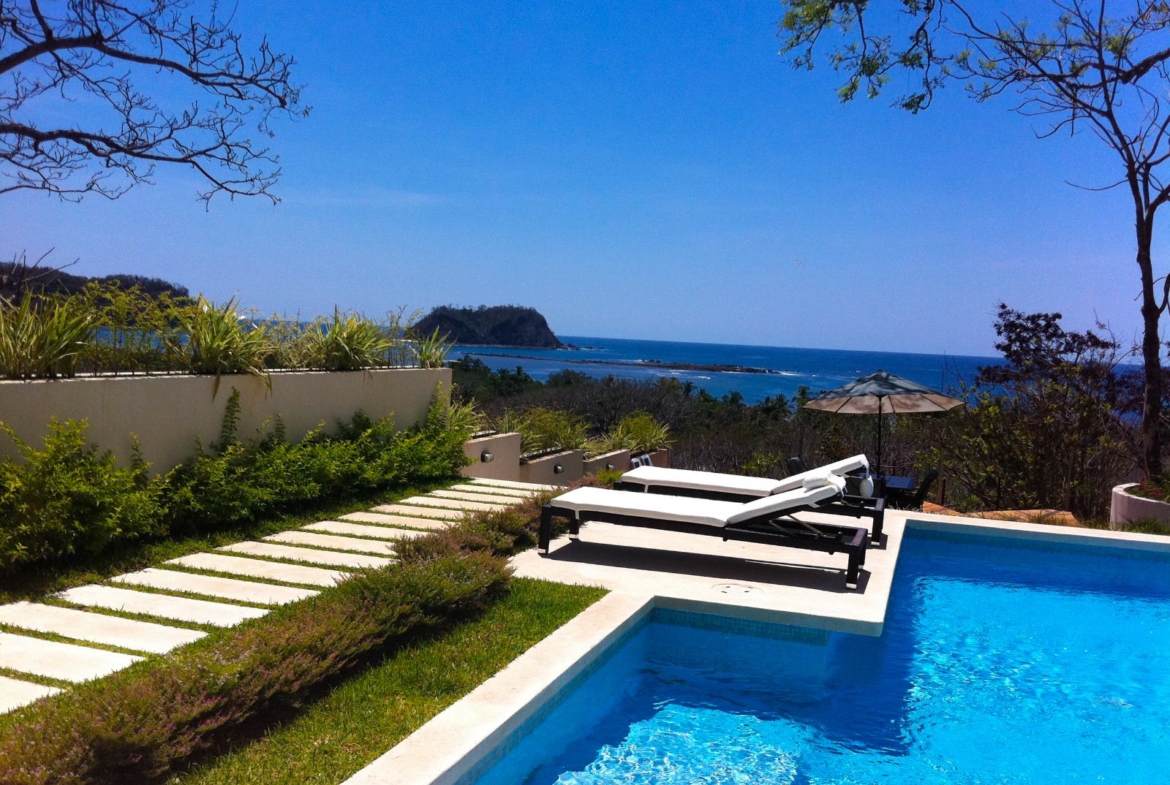 two beach chairs with blue pool overlloking the ocean and Isla Chora Samara Reef Condo for sale samara Guanacaste Costa Rica