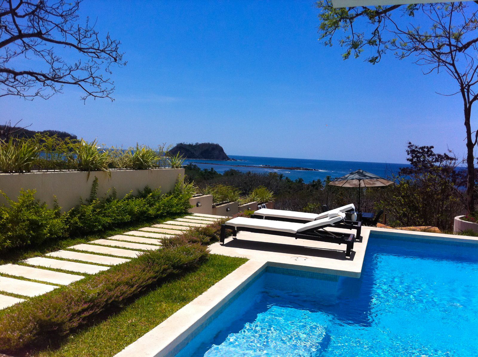 two beach chairs with blue pool overlloking the ocean and Isla Chora Samara Reef Condo for sale samara Guanacaste Costa Rica